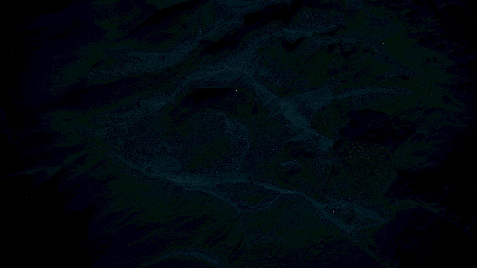 A dark, bluish, rippling ocean surface with deep shadows and scattered tiny lights/specks across the water.