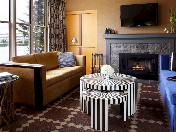 A cozy living room with a fireplace, sofas, TV, and a striped coffee table in front.