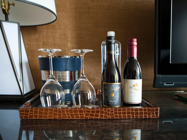 Two wine bottles and four stemmed glasses sit on a table beside a lamp in a cozy bar setting.