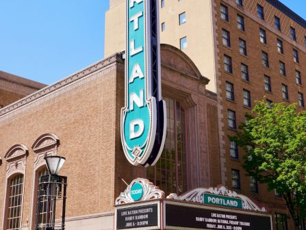 A downtown theater marquee for Portland with a tall sign reading &ldquo;PORTLAND&rdquo; and ads for Live Nation&rsquo;s Randy Rainbow show.