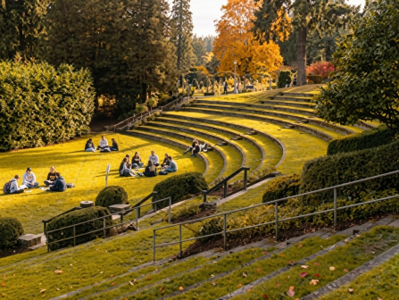 A manicured terraced garden with winding hedges and steps, where groups picnic on the lawn in warm autumn light.