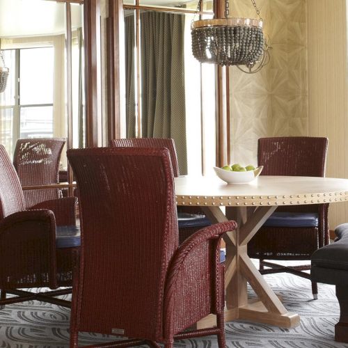 A stylish dining room with a wooden table, cushioned chairs, large windows, and sparkling bead chandeliers overhead.