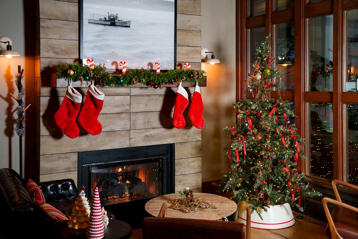 Cozy living room holiday scene: a lit fireplace, Christmas stockings on the mantel, a decorated tree, and festive lights.